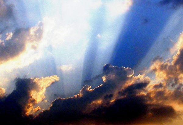 Image of Clouds and sun rays over a blue sky