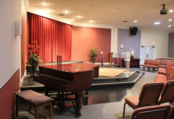 Warm and inviting photo of Center for SPiritual Living, Chico's stage room with mini grand piano and stage view