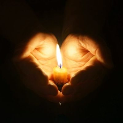 Hands holding a wax candle. Candlelight. Stock image of hands cupping a lite candle.