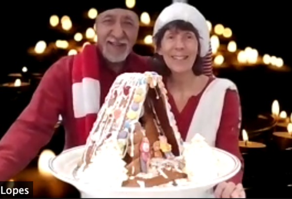 Screen shot of older couple holding up the gingerbread house they just made online in a Christmas zoom event