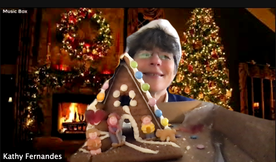 image on online gingerbread house building in zoom. Image of woman holding up gingerbread house from an online event